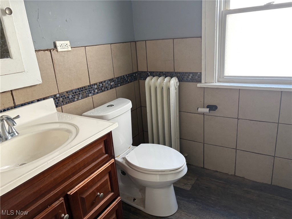 3258 Berkshire Road Cleveland, OH 44118 - Photo 20 of 23 Half bathroom with wood finished floors, tile walls, vanity, radiator, and wainscoting