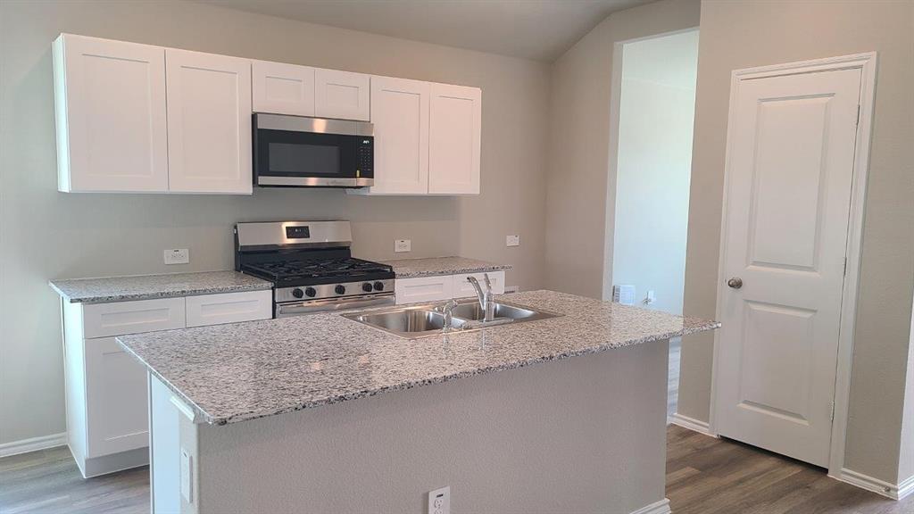 a kitchen with granite countertop a sink and a stove top oven