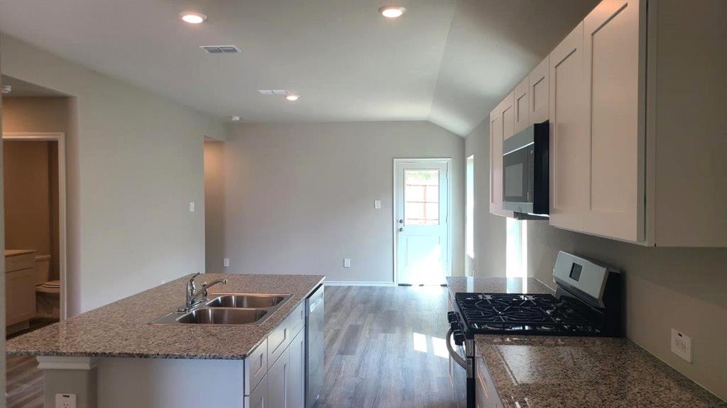 1512 Tin Roof Road Krum, TX 76249 - Photo 2 of 13 a kitchen with granite countertop a stove a sink and a refrigerator