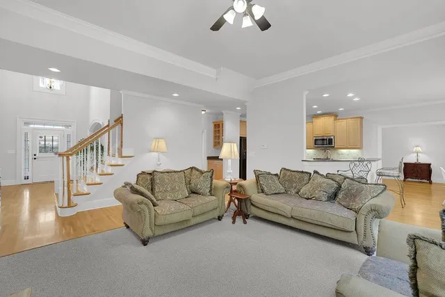 a kitchen with stainless steel appliances kitchen island granite countertop a refrigerator a stove a sink a dining table and chairs with wooden floor