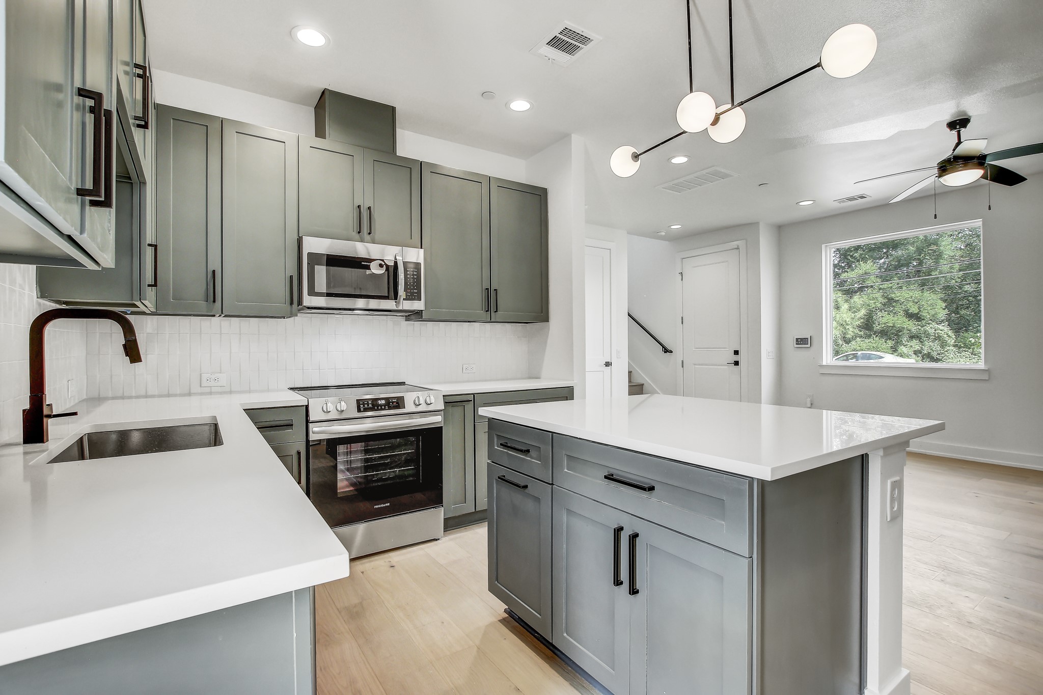 4127 East 12th Street, Unit 3 Austin, TX 78721 - Photo 5 of 29 Kitchen with appliances with stainless steel finishes, a sink, light wood-style flooring, decorative backsplash, and recessed lighting