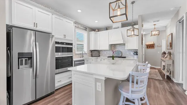 a kitchen with stainless steel appliances kitchen island granite countertop a refrigerator and a stove top oven