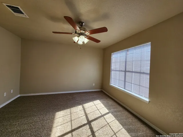 en empty room with windows and ceiling fan