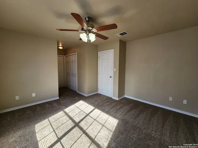 an empty room with windows and fan