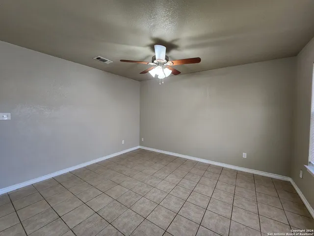 a view of an empty room and chandelier fan