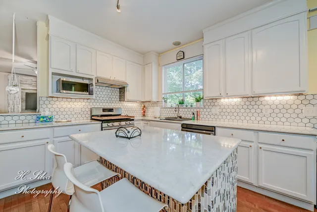 a kitchen with stainless steel appliances granite countertop a stove top oven a sink a counter space and a window