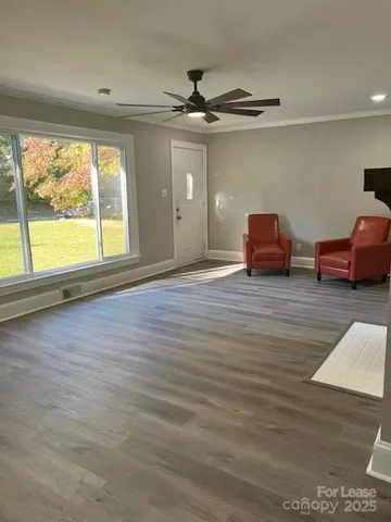 a view of an empty room with wooden floor and a window