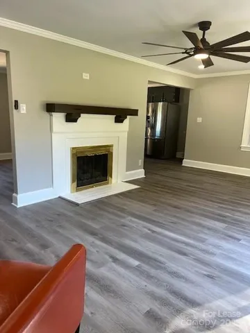 a view of an empty room with wooden floor and a fireplace