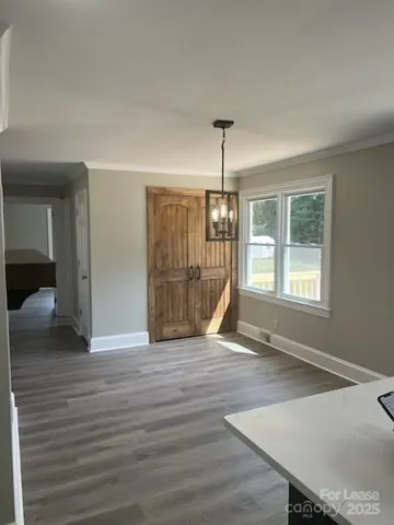 a view of an empty room with wooden floor fridge and a window