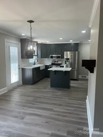 a large kitchen with stainless steel appliances a large counter top a stove and a chandelier