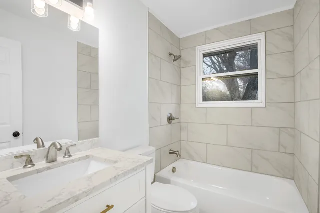 a bathroom with a granite countertop sink a mirror a bathtub and shower