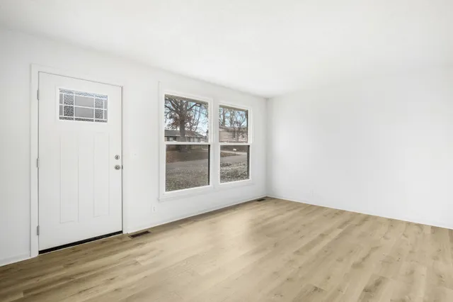 an empty room with wooden floor and windows