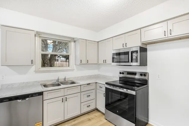 a kitchen with stainless steel appliances a stove microwave and sink