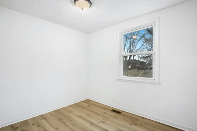 an empty room with wooden floor and window