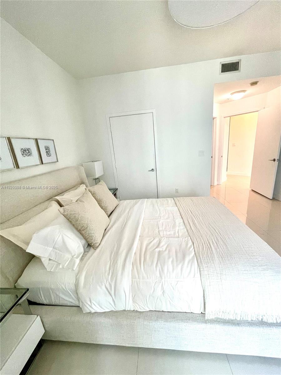 79 Southwest 12th Street, Unit 2407S Miami, FL 33130 - Photo 14 of 35 a bedroom with a bed and a mirror