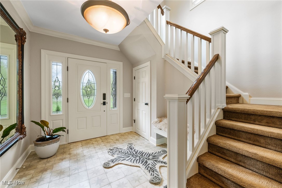 Entrance foyer with stairway, baseboards, and crown molding