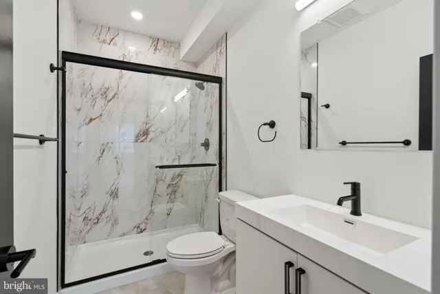 a bathroom with a shower sink vanity mirror and toilet