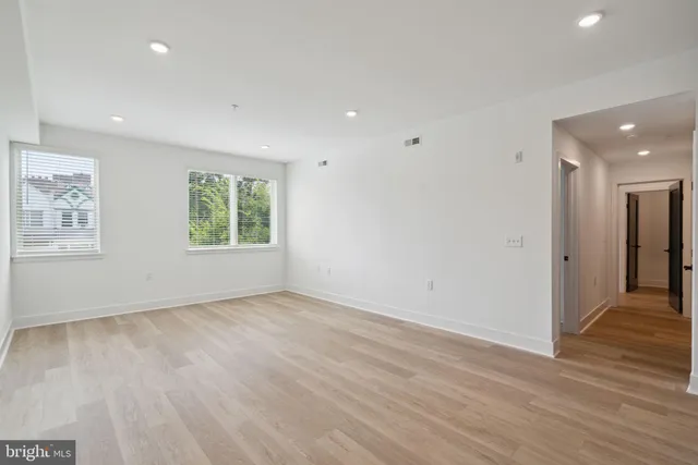 an empty room with wooden floor and windows