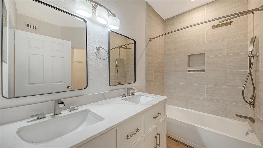 5561 Rosehill Road, Unit 104 Sarasota, FL 34233 - Photo 32 of 53 a bathroom with a sink double vanity granite tub shower and a mirror