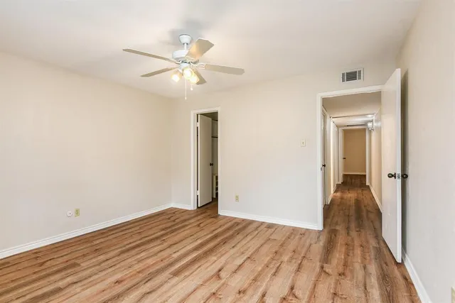 a view of a room with wooden floor closet and ceiling fan