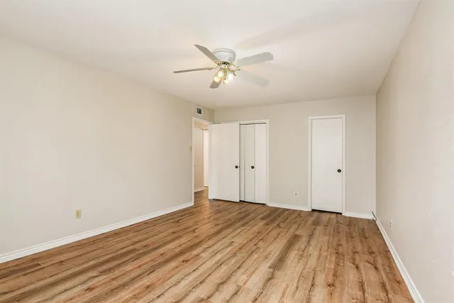 a view of a room with wooden floor and ceiling fan