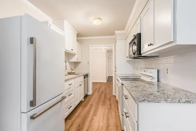 a kitchen with granite countertop white cabinets and white appliances