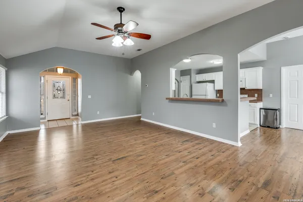 an empty room with wooden floor and a kitchen