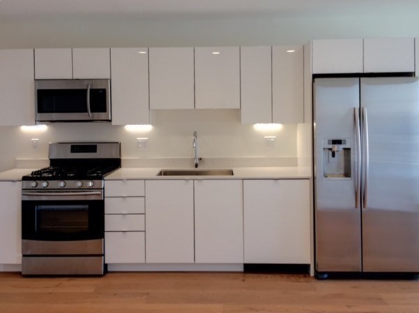 a kitchen with stainless steel appliances white cabinets a sink a stove a microwave and a refrigerator