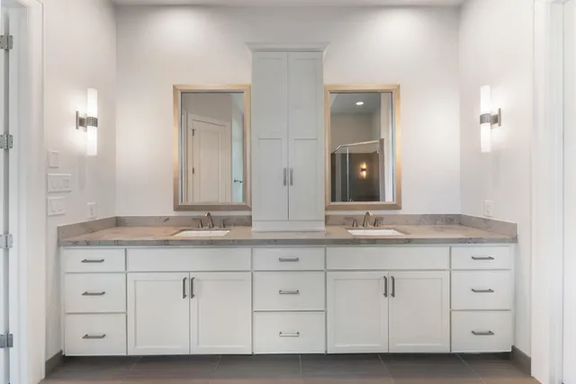 a bathroom with a granite countertop double vanity sink and mirror