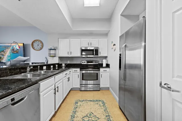 a kitchen with stainless steel appliances granite countertop a refrigerator a stove and a sink with wooden floor
