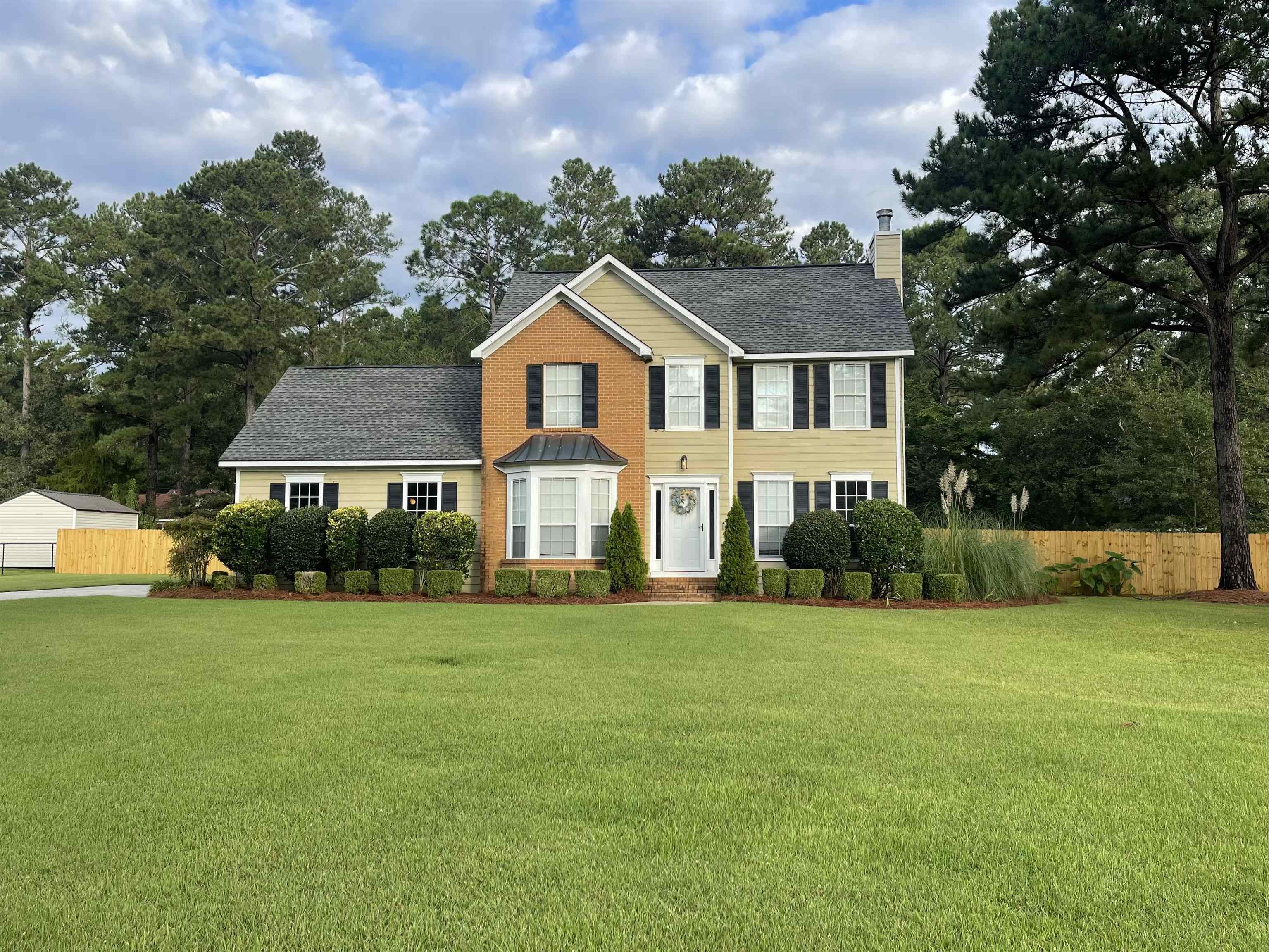 a front view of a house with a yard and trees