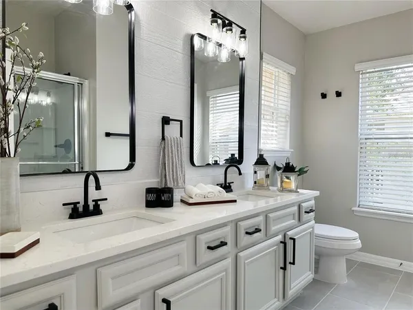 a bathroom with double vanity sink a mirror and a toilet