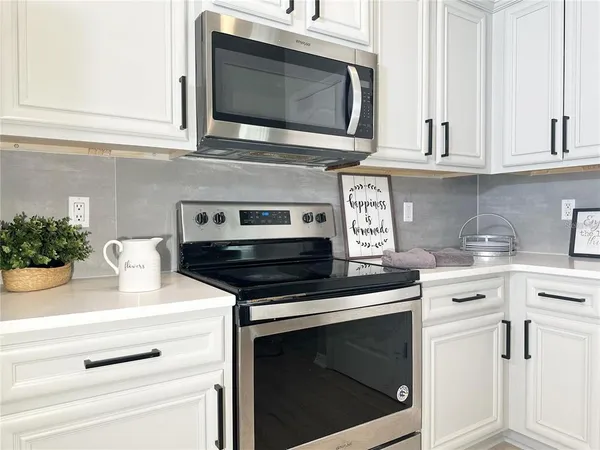 a kitchen with white cabinets and appliances