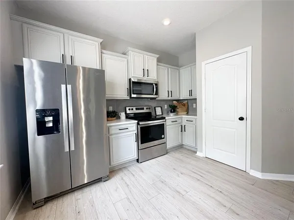 a kitchen with a refrigerator cabinets and wooden floor