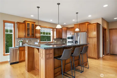a kitchen with stainless steel appliances granite countertop wooden floors and white cabinets