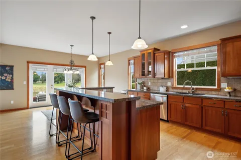 a kitchen with granite countertop a table chairs stove and wooden floor