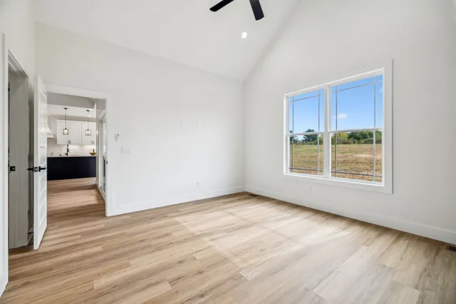 a view of an empty room with wooden floor and a window