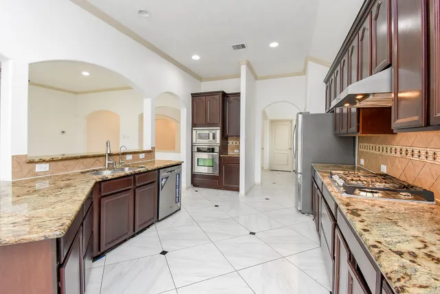 a large kitchen with stainless steel appliances granite countertop a large stove a sink dishwasher and refrigerator
