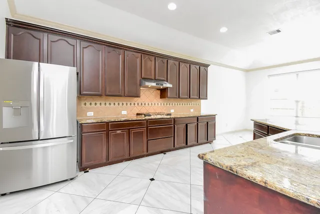 a kitchen with stainless steel appliances granite countertop a refrigerator a stove and a sink