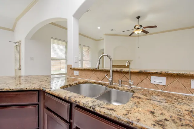 a kitchen with granite countertop a sink a counter top space and cabinets