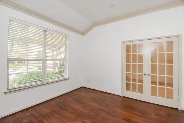 a view of an empty room with wooden floor and a window