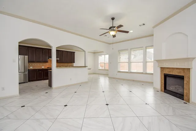 a view of a livingroom with a fireplace a ceiling fan and windows