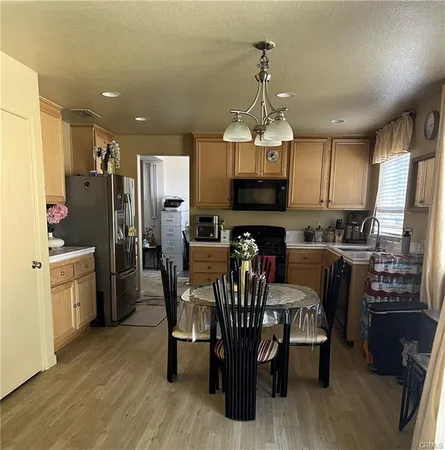 a kitchen with stainless steel appliances granite countertop a refrigerator a stove top oven a sink dishwasher and a dining table with wooden floor