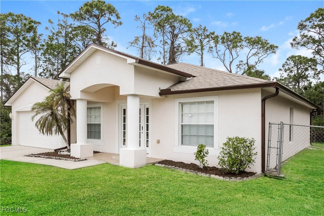 3004 15th Street West Lehigh Acres, FL 33971 - Photo 15 of 16 a view of a white house with a small yard plants and a large tree