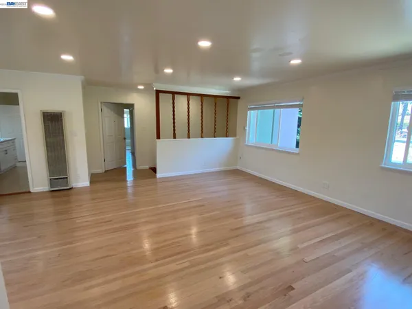an empty room with wooden floor and windows