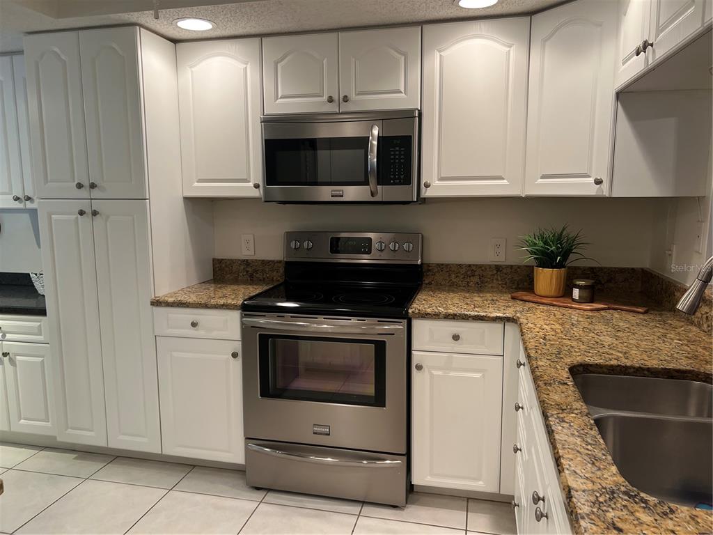 6501 Stone River Road, Unit 309 Bradenton, FL 34203 - Photo 22 of 30 a kitchen with granite countertop white cabinets stainless steel appliances and a sink