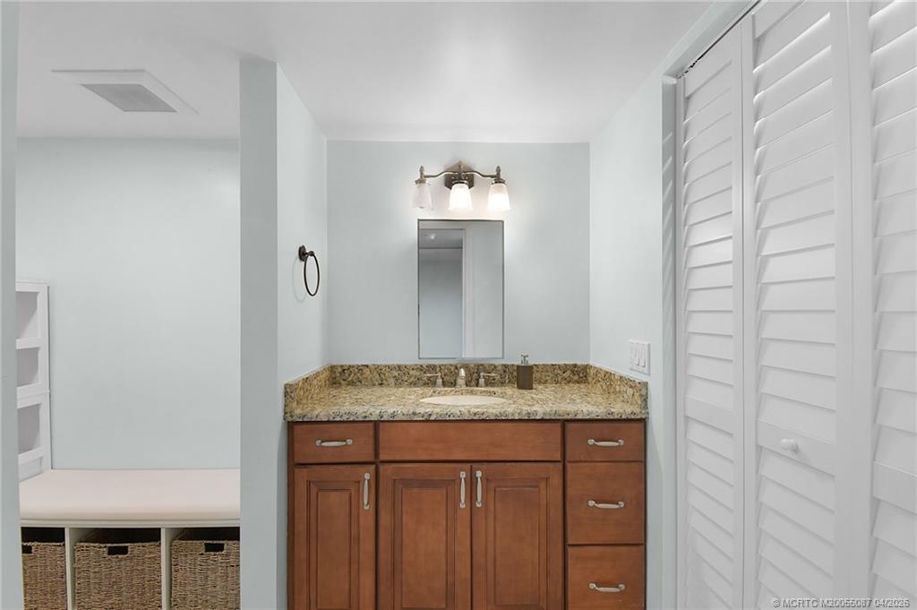 529 Northeast Plantation Road, Unit 105 Jensen Beach, FL 34957 - Photo 22 of 36 a bathroom with a granite countertop sink and a mirror