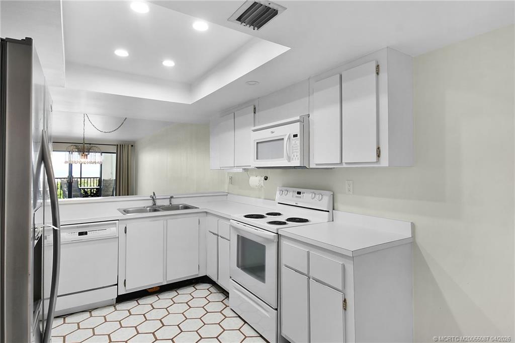 529 Northeast Plantation Road, Unit 105 Jensen Beach, FL 34957 - Photo 8 of 36 a kitchen with white cabinets sink and white appliances