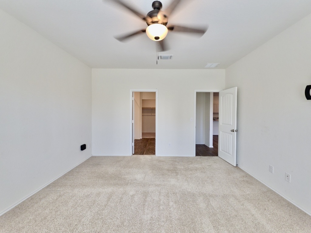13525 Open Wagon Trail Elgin, TX 78621 - Photo 12 of 26 Primary bedroom featuring a walk in closet, carpet floors, and a ceiling fan