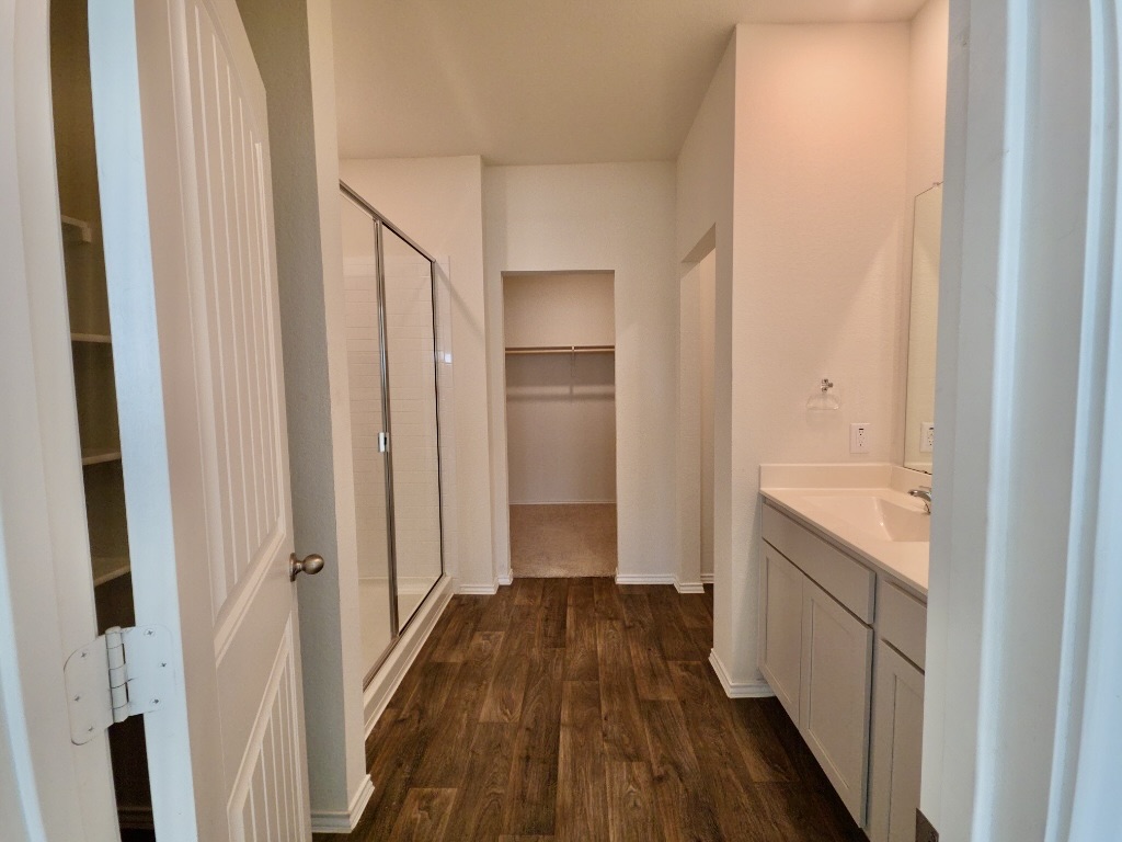 13525 Open Wagon Trail Elgin, TX 78621 - Photo 13 of 26 Full bath with a spacious closet, vanity, dark wood-style flooring, and a stall shower